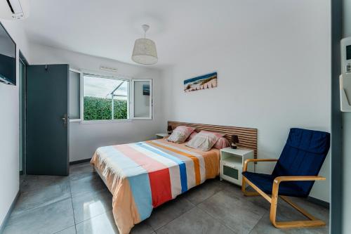 Un dormitorio con una cama y una silla azul. en Villa piscine entre lac et océan, en Cazaux