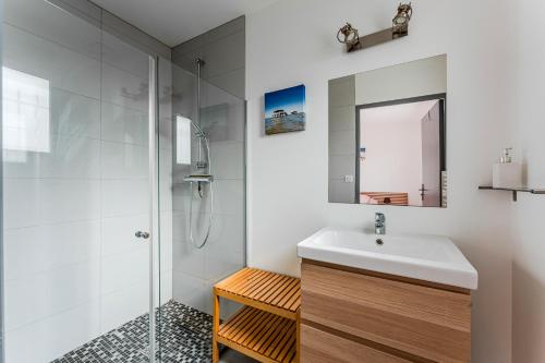 Un baño blanco con lavabo y ducha en Villa piscine entre lac et océan, en Cazaux