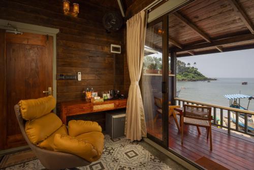 a room with a chair and a desk with a view of the water at The Ark Comforts in Palolem