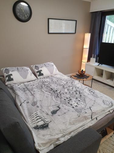 a bed in a living room with a clock on the wall at Luxury 1br apartment in Liminka