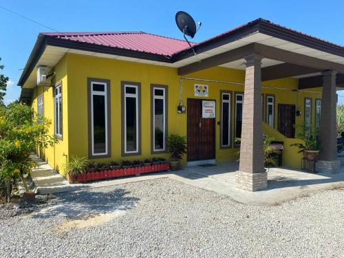 a yellow house with a red roof at Homestay Sri Aliff in Sri Gading