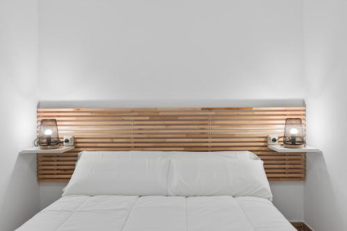 a bedroom with a white bed with two lights on it at Casa Los Naranjos in Marbella