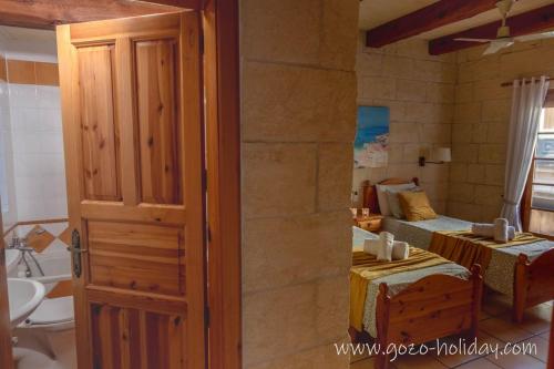 a room with a bedroom with a bed and a bathroom at Hibiscus in Xagħra