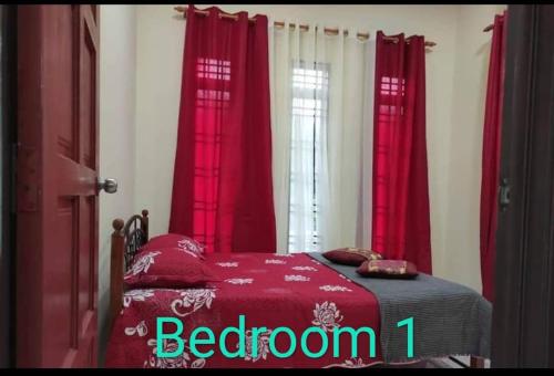 a bedroom with red curtains and a bed with a red blanket at Homestay Sri Aliff in Sri Gading