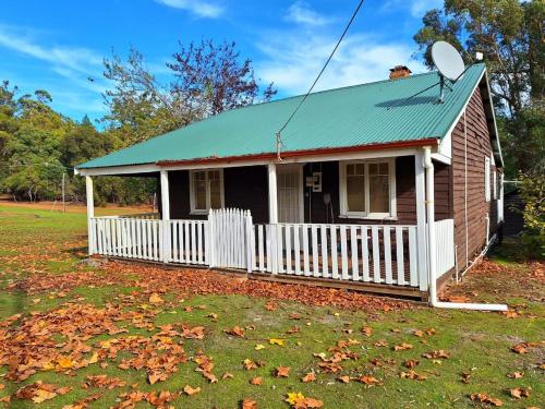 a small house with a white fence in a yard at The May Queen - Footsteps in the Forest in Balbarrup