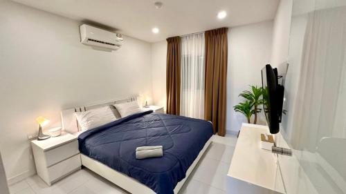 a white bedroom with a blue bed and a tv at Cozy Garden Apartment Butterfly Karon beach in Ban Karon