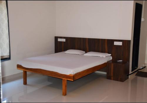 a bed with a wooden headboard in a room at Savali farm stay in Parchuri