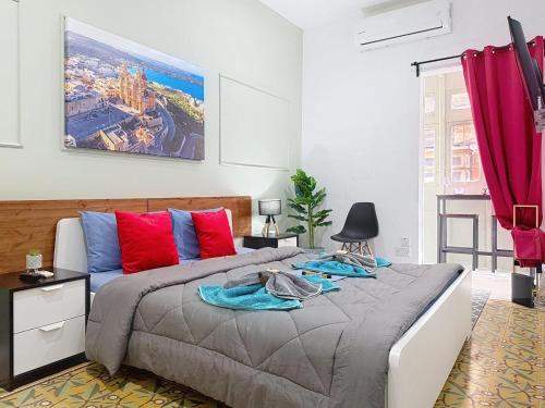 a bedroom with a large bed with red and blue pillows at Modern Studio Apartment1 next to Valletta in Il-Furjana