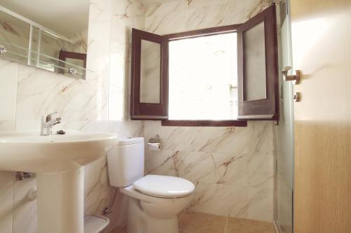 Un baño con inodoro, lavabo y ventana. en Puerta de la Catedral, en Toledo