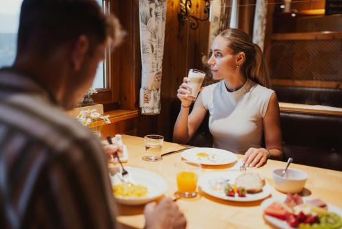 dwoje ludzi siedzących przy stole jedzących jedzenie w obiekcie Hotel Oberland w mieście Triesenberg
