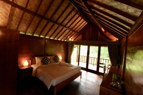 a bedroom with a bed in a room with windows at The Payung House in Bebandem
