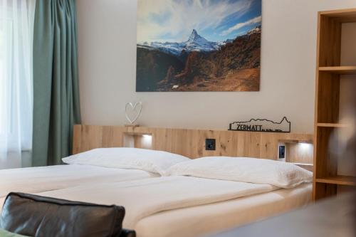 Un dormitorio con una cama con un cuadro en la pared. en Bolero Appartements, en Zermatt