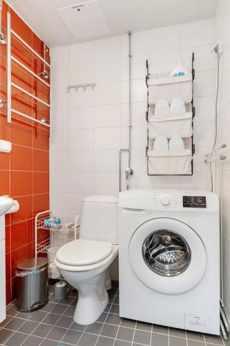 a bathroom with a toilet and a washing machine at Aurora Atelier Design Apartment in Rovaniemi