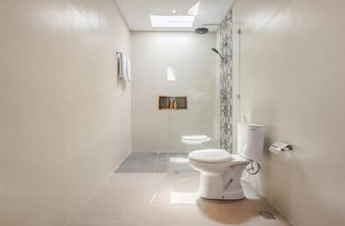 een witte badkamer met toilet en douche bij Okananda Villa Ubud in Ubud