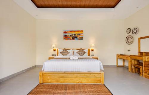 een slaapkamer met een groot bed en een bureau bij Okananda Villa Ubud in Ubud