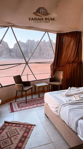 a bedroom with a bed and two chairs and a window at FARAH RUM lUXURY CAMP in Wadi Rum