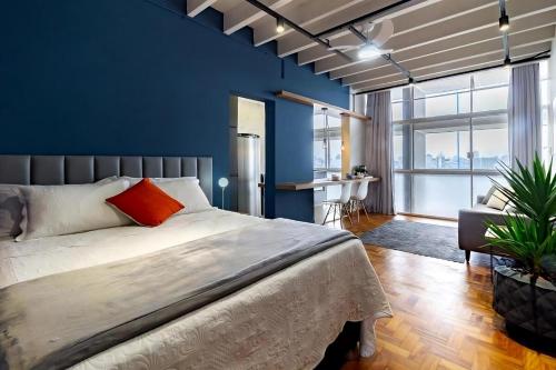 une chambre avec un grand lit et un mur bleu dans l'établissement Copan Castelli Studios SP, à São Paulo