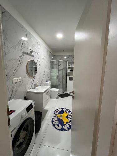 a white bathroom with a sink and a washing machine at Central and Spacious Apartment with All Amenities in Nitra