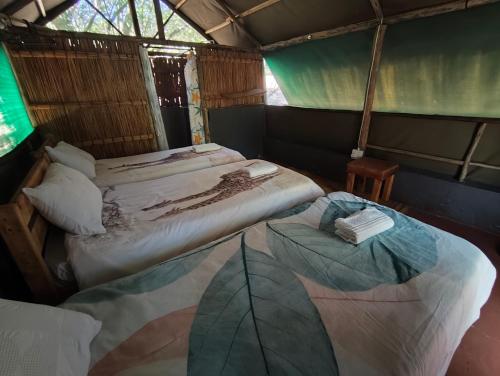 two beds in a small room with at Amangwane Tented Camp in Enkovukeni