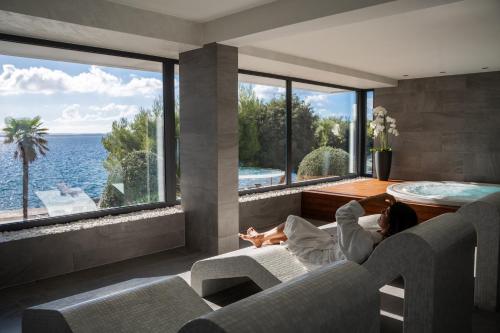 a woman laying in a living room with a view of the ocean at Hotel Pinija in Petrcane