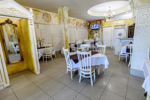 a restaurant with white tables and chairs and a mirror at Pensiunea Paradis in Râmnicu Vâlcea