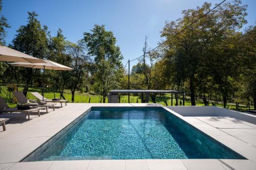 a swimming pool with chairs and an umbrella at Villa Peregrine Plitvice Lakes 