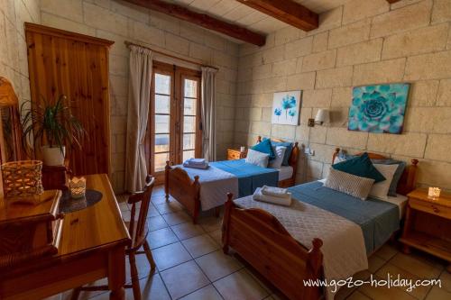 a bedroom with two beds and a table at Hibiscus in Xagħra