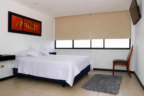 une chambre avec un lit, une chaise et une fenêtre dans l'établissement Bellini, Hermoso Departamento y 1 Plaza de Parqueo Gratis, à Guayaquil
