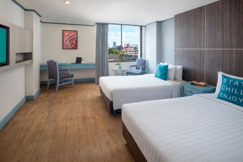 a hotel room with two beds and a desk at Cross Vibe Bangkok Srinakarin in Bangkok