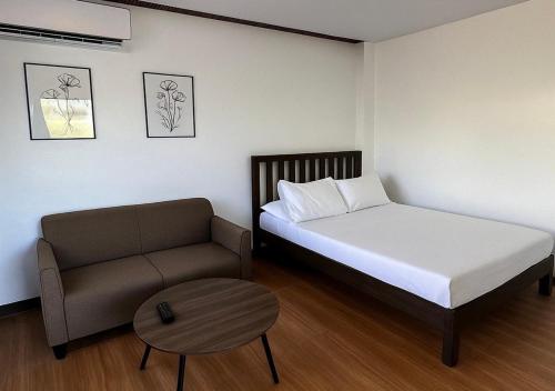 a bedroom with a bed and a couch and a table at Balai de Biday 4 Pax Suite with Free Breakfast in Mameltac
