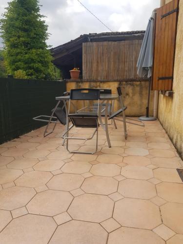 a patio with a table and chairs and an umbrella at Maison dans un village calme in Carla-de-Roquefort