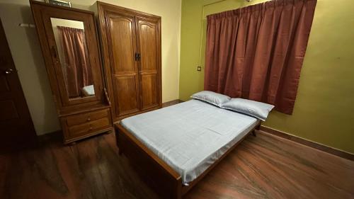 ein kleines Schlafzimmer mit einem Bett und einem Holzschrank in der Unterkunft Indeevaram in Kochi