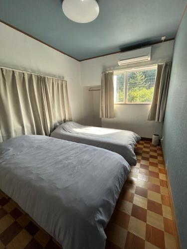 two beds in a small bedroom with a window at ゲストハウスはれのち in Furunoushigawa