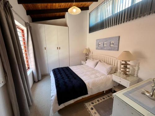 een slaapkamer met een bed, een bureau en een raam bij SeaSalt Rest in Plettenbergbaai