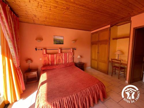 une chambre avec un lit et un bureau dans une pièce dans l'établissement Le gîte du Puech de Fons, à Le Cayrol