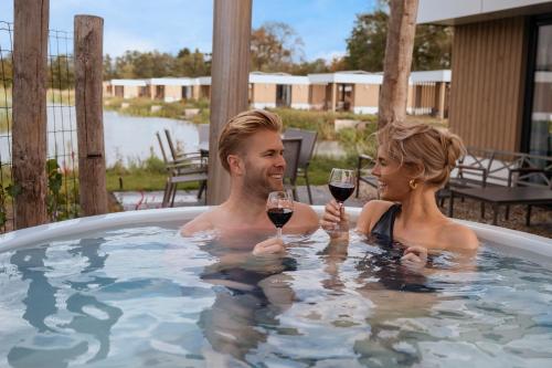 a man and woman holding glasses of wine in a hot tub at Hofparken Wiltershaar in Winterswijk