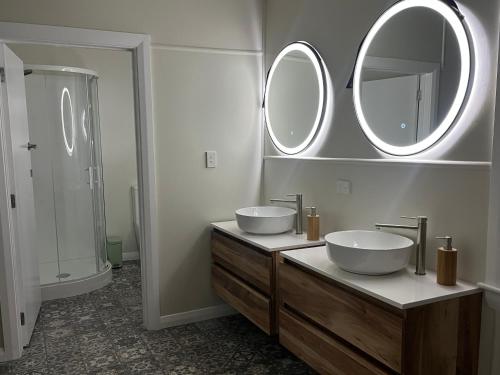 a bathroom with two sinks and two mirrors at Nourish Reefton & Wilsons Hotel in Reefton