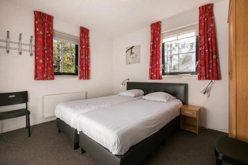 a bedroom with a bed and two windows with red curtains at Zandduin Villa met Sauna | 10 personen in Hooghalen