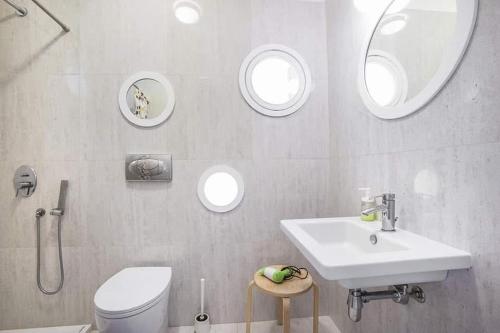 ein Badezimmer mit Waschbecken, Toilette und Spiegeln in der Unterkunft Municipio 25 in Corigliano Calabro