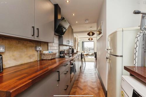 a kitchen with white cabinets and a wooden counter top at Duplex Apartment Harbourside city centre in Bristol
