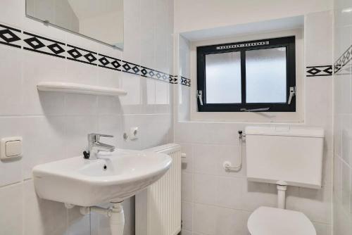 a white bathroom with a sink and a toilet at Stuifzand Bungalow | 8 personen in Hooghalen