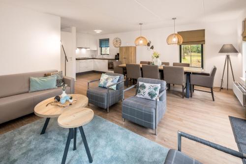 a living room with a couch and a table at Stuifzand Wellness Bungalow | 8 personen in Hooghalen