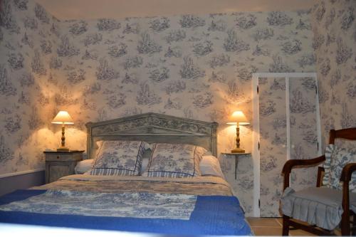 ein Schlafzimmer mit einem Bett mit zwei Lampen und zwei Stühlen in der Unterkunft Haut du Blanc in Le Blanc