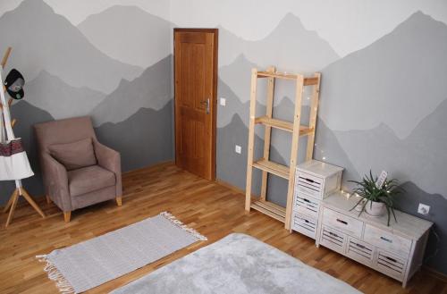 a room with a chair and a book shelf and a room with mountains painted on at Cosy Dream Appartment near Borovets in Samokov