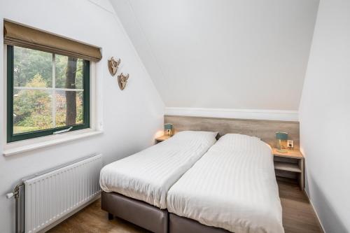 a bedroom with a bed and a window at Vennenhof Wellness Bungalow | 6 personen in Hooghalen