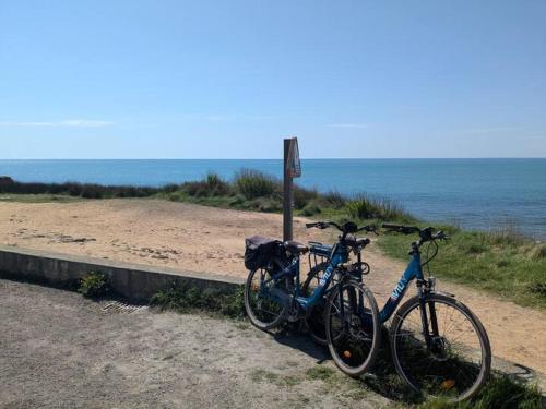 twee fietsen geparkeerd naast een bord op het strand bij Villa Angeli in Les Sables-dʼOlonne