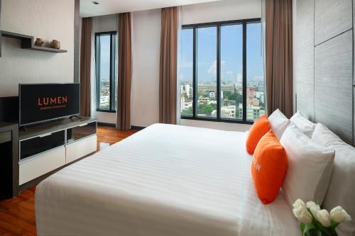 a hotel room with a large white bed with orange pillows at Lumen Bangkok Srinakarin in Bangkok