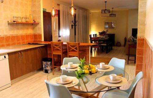 a kitchen and dining room with a glass table and chairs at Casa de la Senda in Candeleda