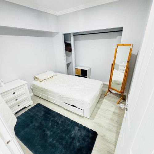 una camera da letto bianca con un letto e uno specchio di Charming Cozy Stay In Heart Of St Albans a St Albans