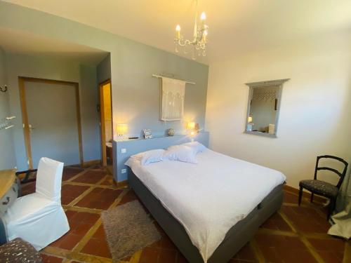 a bedroom with a white bed and a chair at Ferme de Montecouvez in Crèvecoeur-sur-lʼEscaut